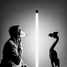Person holding funnel as mask gazes at wooden sculpture of bird