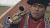 Indigenous man holding instrument